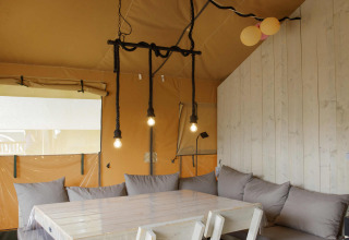 Innenaufnahme eines Safari-Zeltes bei Costa Kabrita in den Niederlanden mit Tisch, Stühlen und Sofa.