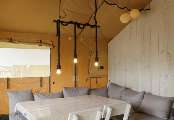 Innenaufnahme eines Safari-Zeltes bei Costa Kabrita in den Niederlanden mit Tisch, Stühlen und Sofa.