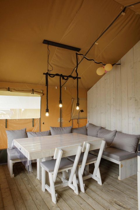 Innenaufnahme eines Safari-Zeltes bei Costa Kabrita in den Niederlanden mit Tisch, Stühlen und Sofa.