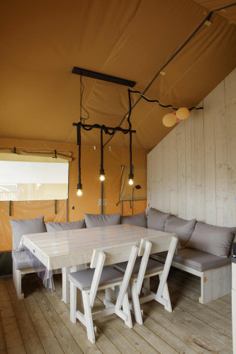 Vista interior de la tienda Safari en Costa Kabrita, Países Bajos, con mesa de comedor, sillas y sofá.