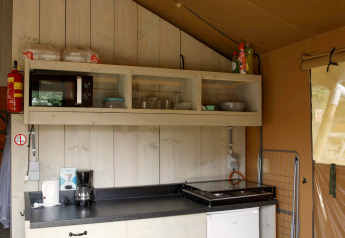 Køkkenområde i en safaritelt lodge på Costa Kabrita i Holland, med hylder, komfur og minikøleskab.