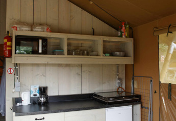 Küchenbereich eines Safari-Zelts in Costa Kabrita, Niederlande, mit Regalen, Kochplatte und Minikühlschrank.