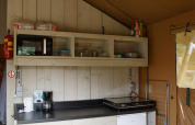 Küchenbereich eines Safari-Zelts in Costa Kabrita, Niederlande, mit Regalen, Kochplatte und Minikühlschrank.