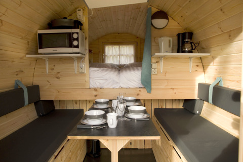 Knus tiny house-interieur bij Wijnvat op Costa Kabrita, Nederland, met eettafel en keukenapparatuur.