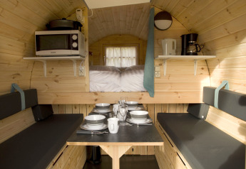 Cozy tiny house interior at Wijnvat, Costa Kabrita, Netherlands with dining table, microwave, and beds.