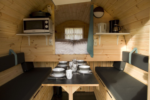 Intérieur confortable d'une tiny house au Wijnvat de Costa Kabrita, Pays-Bas, avec table et cuisine.