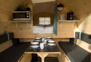 Gemütliches Tiny-House-Interieur im Wijnvat bei Costa Kabrita, Niederlande, mit Esstisch und Küche.