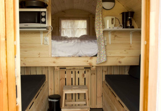 Binnenkant van tiny house Wijnvat met houten interieur, slaapzolder en keukentje bij Costa Kabrita in Nederland.