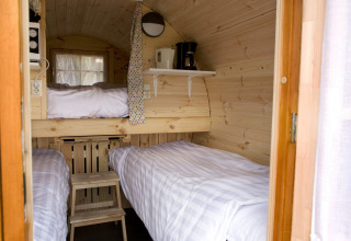 Interieur van het tiny house Wijnvat bij Costa Kabrita, Nederland, met stapelbedden en koffiezetapparaat.
