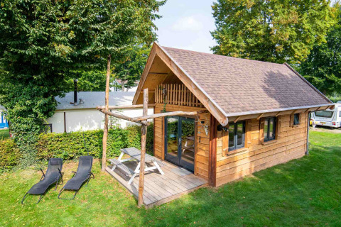 Pequeña casa de madera Jachthut en Camping Vinkenhof, Países Bajos, con terraza, mesa y tumbonas.