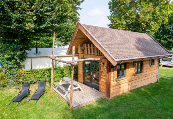 Kleine Holzhütte namens Jachthut auf Camping Vinkenhof mit Terrasse, Picknicktisch und Liegestühlen.