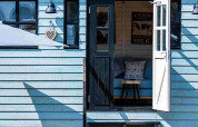 Alojamiento glamping Shepperd Lodge de color azul con puerta abierta, escaleras y área interior acogedora.