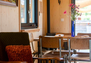 Gemütlicher Innenraum des Tiny House Jachthut auf Camping Vinkenhof, Niederlande, mit Holzmöbeln.