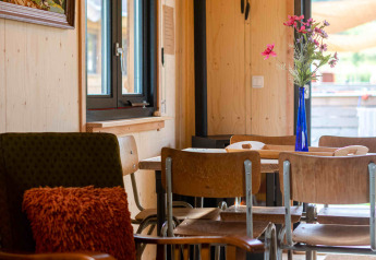 Gezellige woonkamer in het Jachthut tiny house op Camping Vinkenhof, Nederland, met rustieke inrichting.