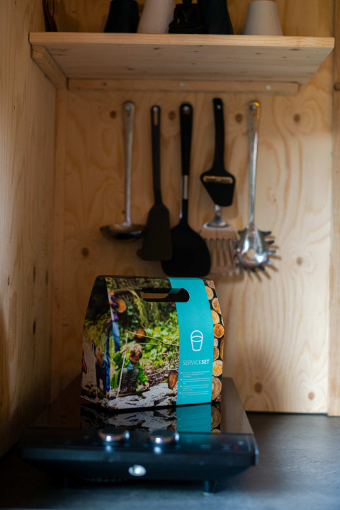 Cocina pequeña con utensilios y set de servicio en la tiny house Jachthut en Camping Vinkenhof.