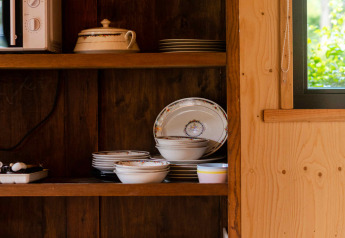 Küchenregal in einem Tiny House in Camping Vinkenhof, Niederlande, mit Geschirr und Küchengeräten.