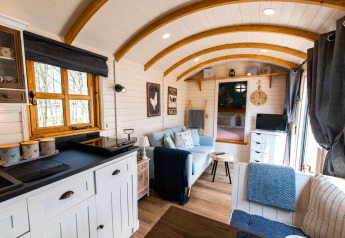 Hébergement glamping Shepperd Lodge confortable avec intérieur en bois, kitchenette et coin salon.