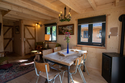 Cozy living room in Jachthut tiny house at Camping Vinkenhof in the Netherlands, featuring wooden furniture.