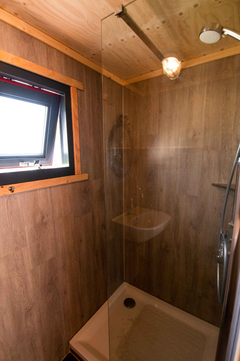 Modern shower in a tiny house at Jachthut, Camping Vinkenhof in the Netherlands, with wood-paneled walls.