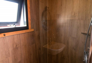 Moderne Dusche in einem Tiny House bei Jachthut auf Camping Vinkenhof in den Niederlanden mit Holzdekor.