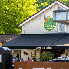 Vista del Café Restaurante Viva La Vink en Camping Vinkenhof, rodeado de árboles en Limburg, Países Bajos.