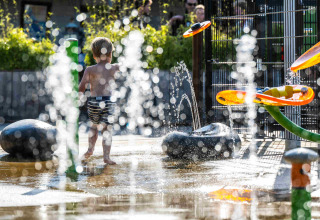 Bambino che gioca tra le fontane d'acqua nel parco acquatico di Camping Vinkenhof, Limburgo, Paesi Bassi.