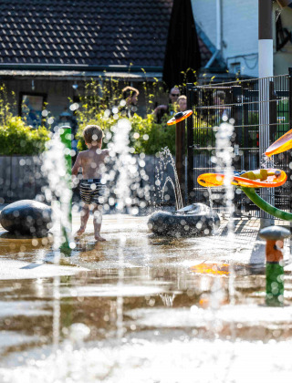 Niño jugando en fuentes de agua en el parque acuático de Camping Vinkenhof, Limburg, Países Bajos.