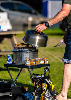 Cocina al aire libre en Camping Vinkenhof con parrilla, frascos de especias y lata de cerveza.