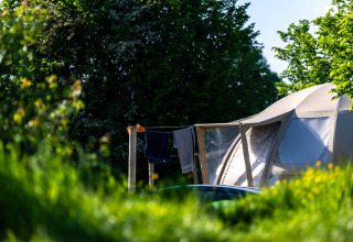 Tent met waslijn en kleding in groene omgeving bij Camping Vinkenhof, Limburg, Nederland, op zonnige dag.
