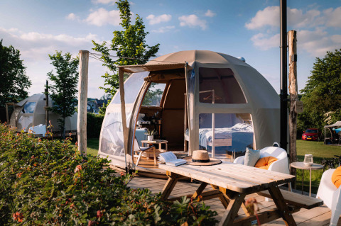 Cúpula Panorama Dome de glamping de lujo con terraza de madera, mesa de pícnic y vistas al jardín.