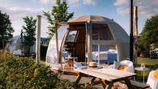 Panorama Dome: tenda glamping di lusso con patio in legno, tavolo da picnic e zona relax all’aperto.