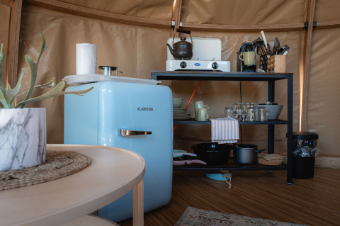 Pequeña cocina en el Panorama Dome en Camping Vinkenhof, Países Bajos, con nevera azul y estantería.