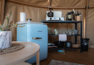 Pequeña cocina en el Panorama Dome en Camping Vinkenhof, Países Bajos, con nevera azul y estantería.