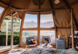 Vista interior del Panorama Dome en Camping Vinkenhof, Países Bajos, con mobiliario moderno y paisaje verde.