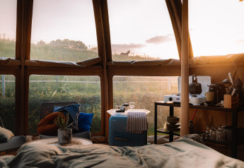 Vista interna del Panorama Dome al Camping Vinkenhof nei Paesi Bassi con arredamento accogliente al tramonto.