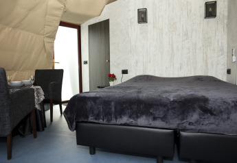 Habitación moderna en la cabaña Dome de Costa Kabrita, Países Bajos, con cama doble y zona de comedor.