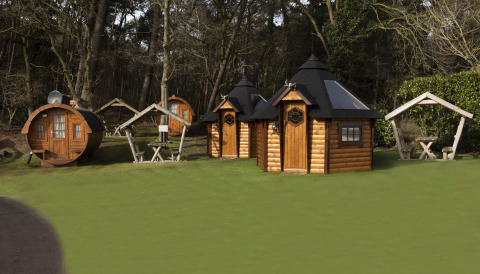 Kleine Holzhäuser und Weinfass-Hütte im Grünen bei Costa Kabrita, Niederlande, umgeben von Wald.