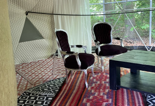 Binnenzicht van de Dome Tent bij Buytenplaets Abelen in Nederland met klassieke stoelen en kleurrijke tapijten.