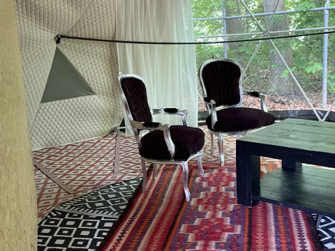 Vista interior de la Dome Tent en Buytenplaets Abelen, Países Bajos, con sillas elegantes y coloridas alfombras.
