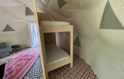 Inde i Dome Tent ved Buytenplaets Abelen, Holland, ses køjeseng, farverige tæpper og quiltede vægge.