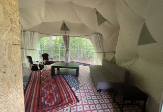 Interieur van de Dome Tent bij Buytenplaets Abelen in Nederland met modern meubilair en zicht op het bos.