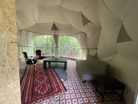 Innenraum des Dome Tents bei Buytenplaets Abelen in den Niederlanden, mit stilvollen Möbeln und Waldblick.