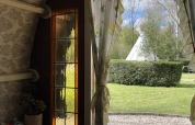 Udsigt fra Gipsy Wagon ved Buytenplaets Abelen i Holland med tipi, grøn hæk og blomstrede gardiner.