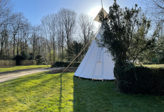 Una tienda tipi llamada Tipi en Buytenplaets Abelen, Países Bajos, rodeada de césped verde y árboles.
