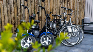 Bicicletas eléctricas y convencionales aparcadas junto a una valla de madera en un parque de glamping.