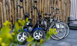 Bicicletas eléctricas y convencionales aparcadas junto a una valla de madera en un parque de glamping.