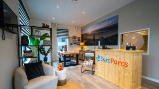 Recepción de un parque vacacional con decoración moderna y logo de EuroParcs, ofrece glamping.