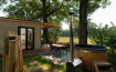Outdoor area of a tiny house with wooden facade, sauna, and hot tub at Holiday Park Mölke, Netherlands.