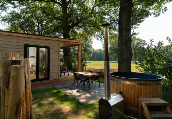 Buitenruimte aan een tiny house met houten gevel, sauna en hottub bij Holiday Park Mölke, Nederland.