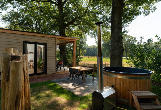 Zona exterior de una tiny house con fachada de madera, sauna y jacuzzi en Holiday Park Mölke, Países Bajos.